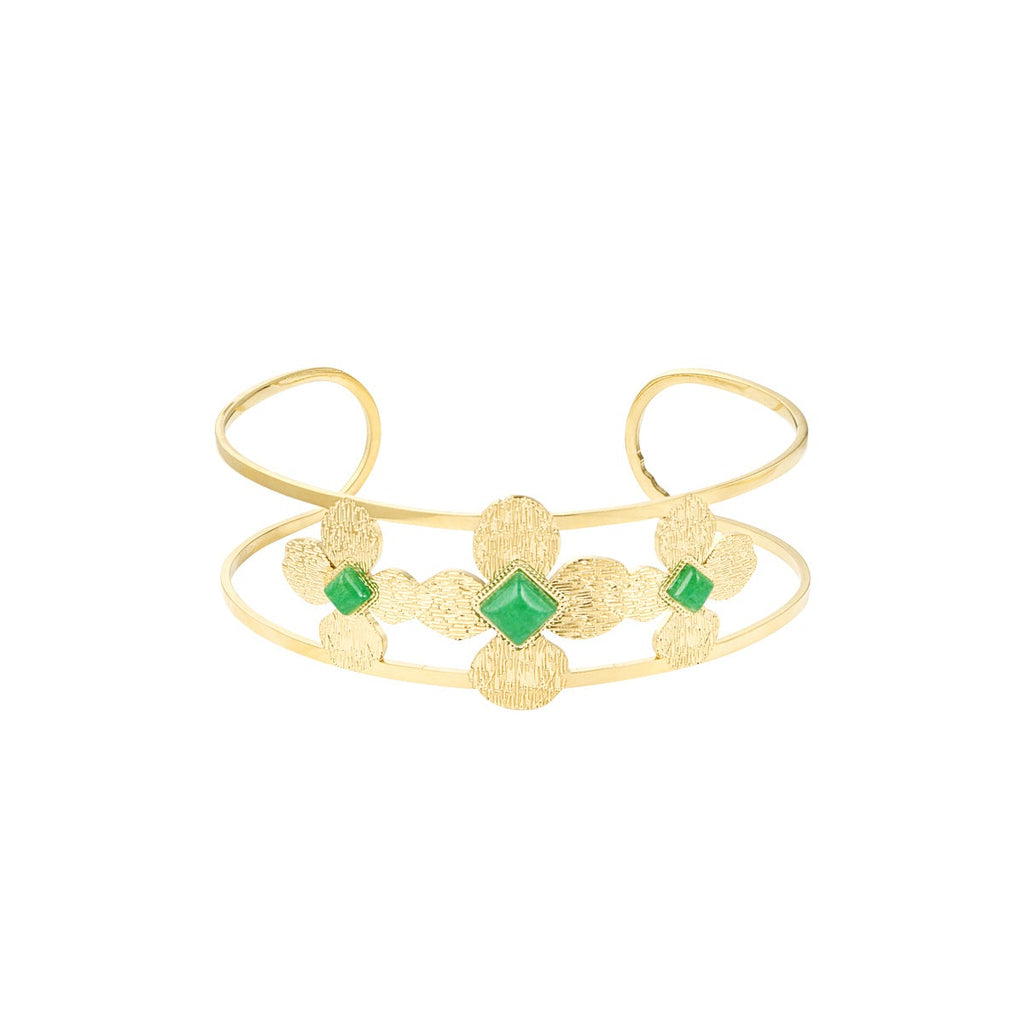 A gold-plated open cuff bangle bracelet featuring a central floral motif with green gemstone accents, set against a plain white background.