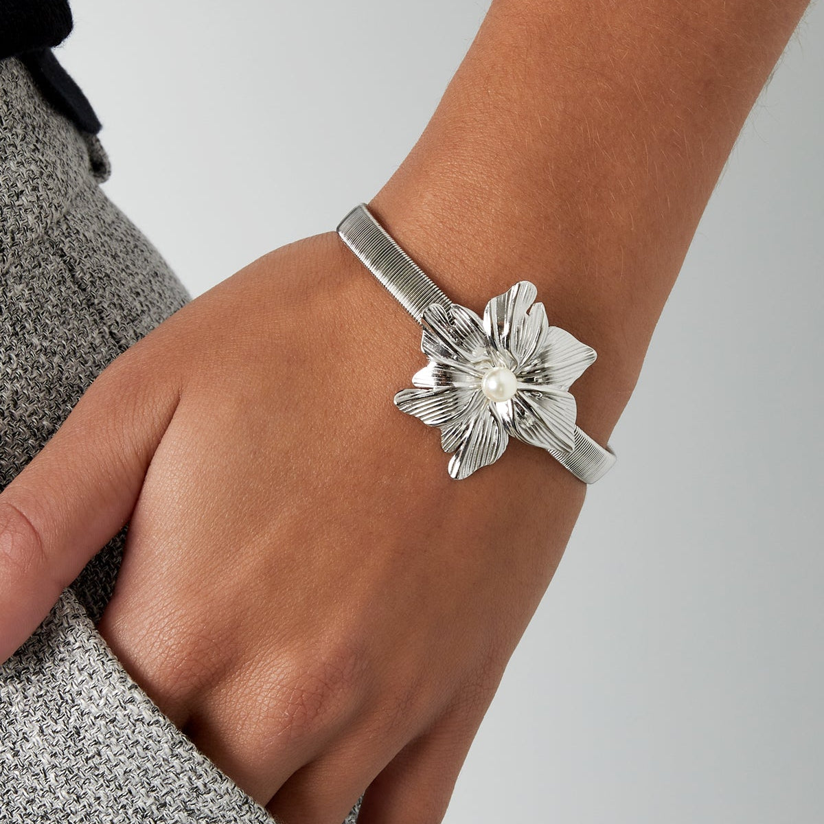 Silver floral bracelet on a wrist against a neutral background